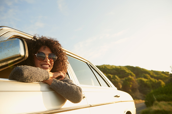 young woman sitting in car, wearing sunglasses